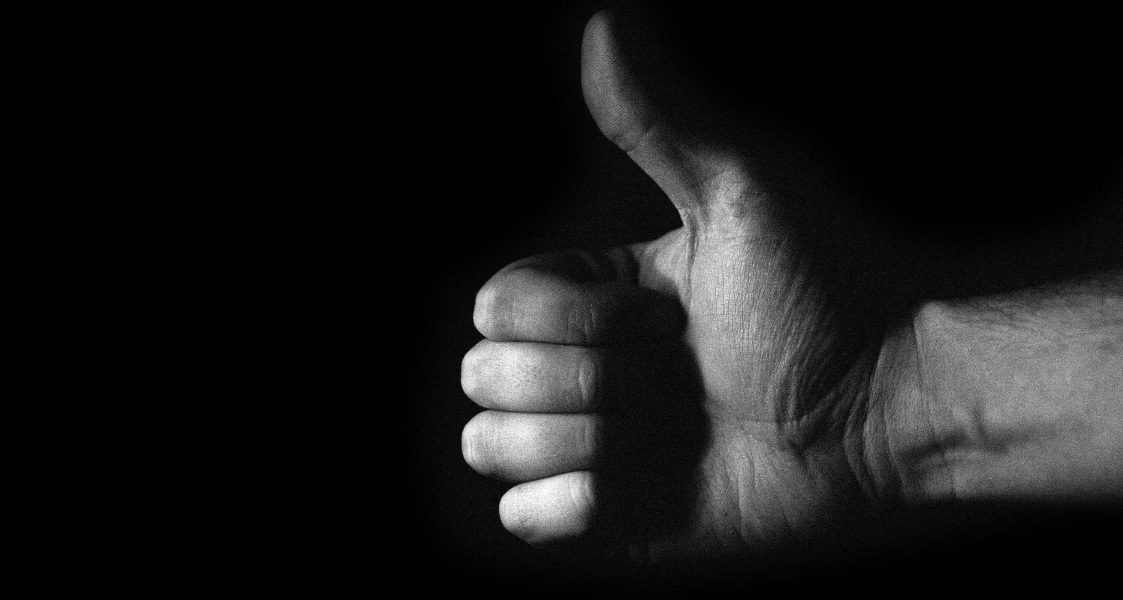 Eine Hand, die den Daumen nach oben streckt auf schwarzem Hintergrund